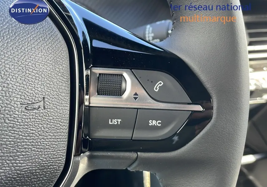 Gros plan sur les commandes gauche du volant en cuir noir du Peugeot 2008 blanc Okenite Metal, modèle 2025.