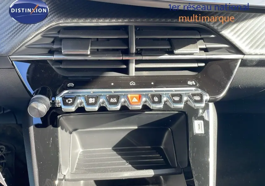 Vue rapprochée de la console centrale noire du Peugeot 2008 blanc, avec boutons de commande et aérateurs visibles.