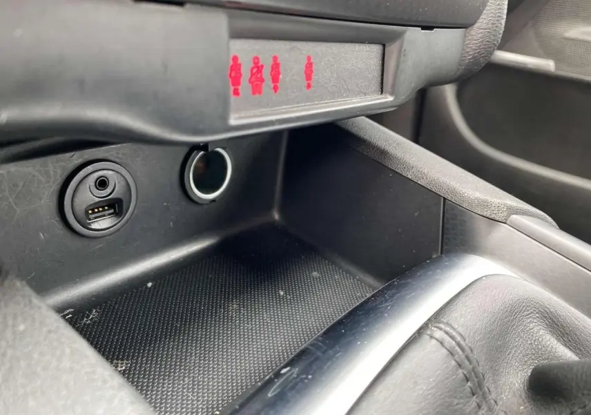 Prise USB et allume-cigare dans la console centrale d'une DS4 2016, avec indicateurs de ceinture allumés en rouge.