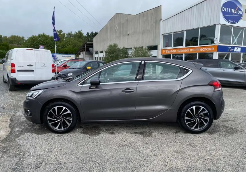 Profil côté gauche d'une DS4 gris clair 2016 avec jantes alliage et lignes fluides, stationnée en extérieur devant un bâtiment.