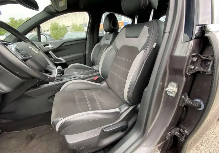 Vue intérieure côté conducteur du DS4 gris clair de 2016, montrant les sièges en tissu et alcantara noirs avec surpiqûres grises.