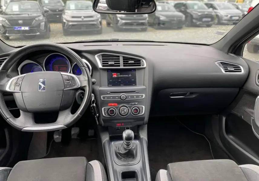 Tableau de bord et console centrale noirs d'une DS4 2016 avec volant multifonction et boîte manuelle visible.