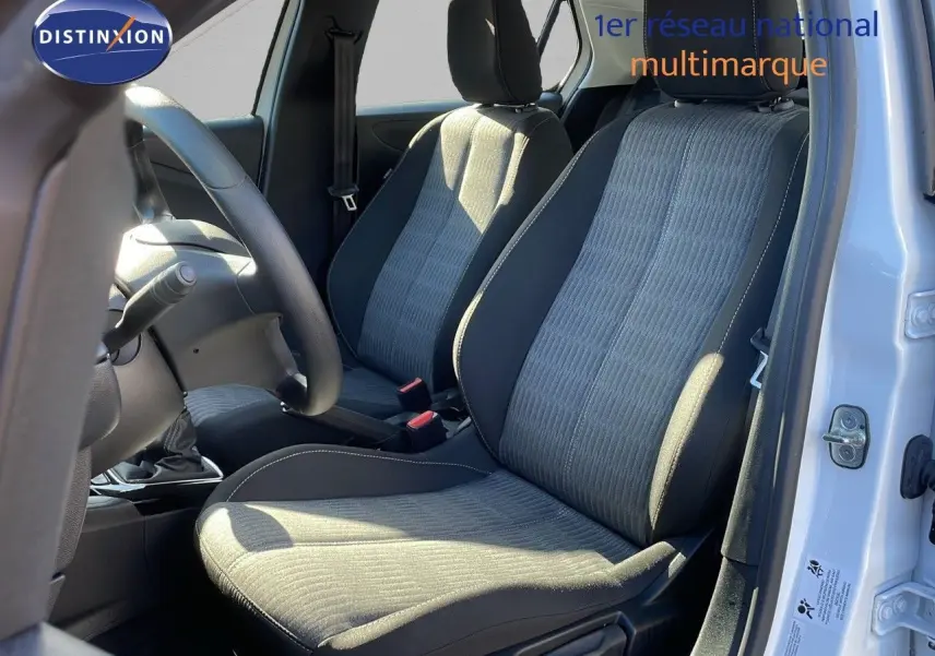 Vue intérieure côté conducteur de l'Opel Corsa blanc glacier 2022, sièges tissu gris et noir avec volant visible.