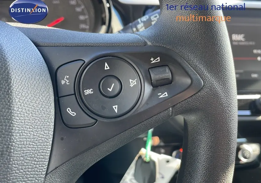 Gros plan sur les commandes au volant noir de l’Opel Corsa blanc glacier 2022, mettant en valeur les boutons multifonctions.