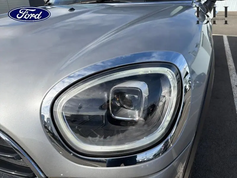 Gros plan sur le phare avant droit chromé d'une MINI COUNTRYMAN Melting Silver III 2023, soulignant son design moderne.