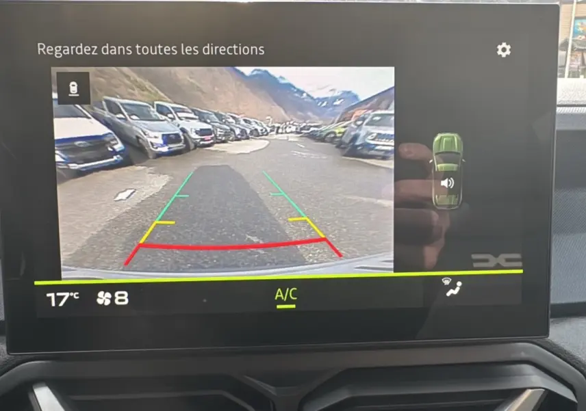 Écran central du Dacia Duster 2025 affichant la caméra de recul avec vue arrière et indications de trajectoire.