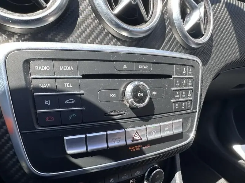 Vue rapprochée de la console centrale d’une Mercedes Classe A 200 d Fascination blanche, avec commandes multimédia et aérateurs ronds.