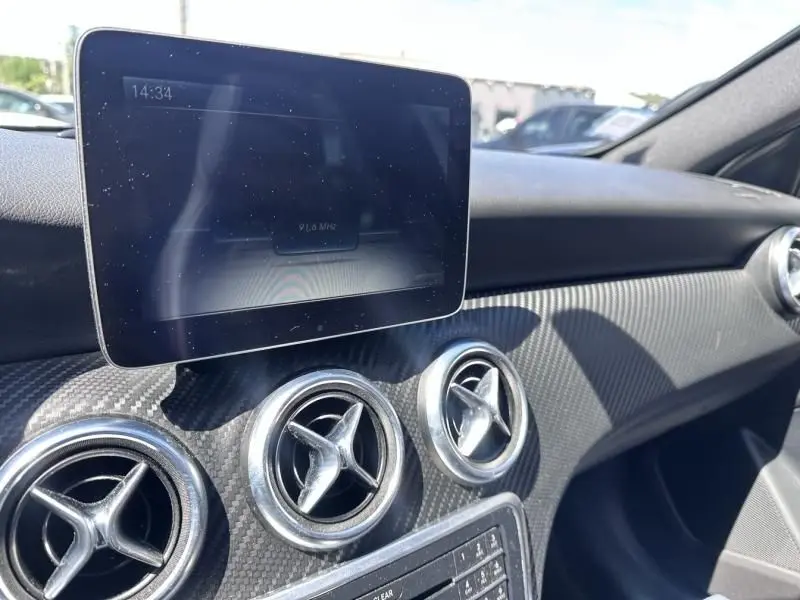Vue rapprochée de la planche de bord d’une Mercedes Classe A 200 d Fascination 2017, avec écran tactile et aérateurs ronds chromés.