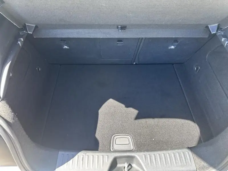 Coffre vide vu de dessus d’une Mercedes Classe A 200 d Fascination blanc 2017, intérieur noir et tapis propre.