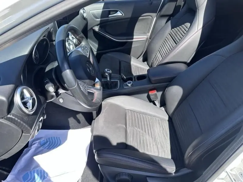 Vue intérieure côté conducteur de la Mercedes Classe A 200 d Fascination 2017, sièges noirs avec surpiqûres rouges et volant multifonction.