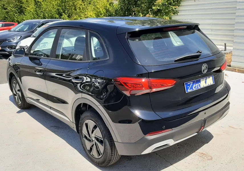 Vue 3/4 arrière droite du MG ZS 1.5L Hybrid+ 2026 en noir Pebble Black Metal avec feux arrière LED et jantes spécifiques.
