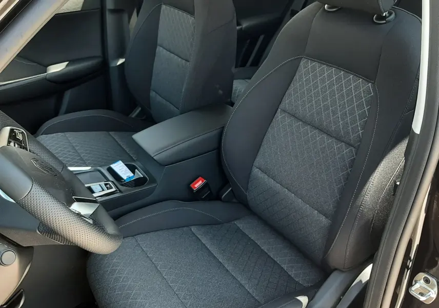 Vue intérieure côté conducteur du MG Motor ZS 1.5L Hybrid+ 2026, sièges tissu noir avec surpiqûres grises.