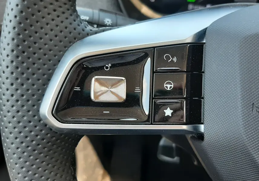 Gros plan sur les commandes multifonctions à gauche du volant perforé noir du MG MOTOR ZS hybride 2026.