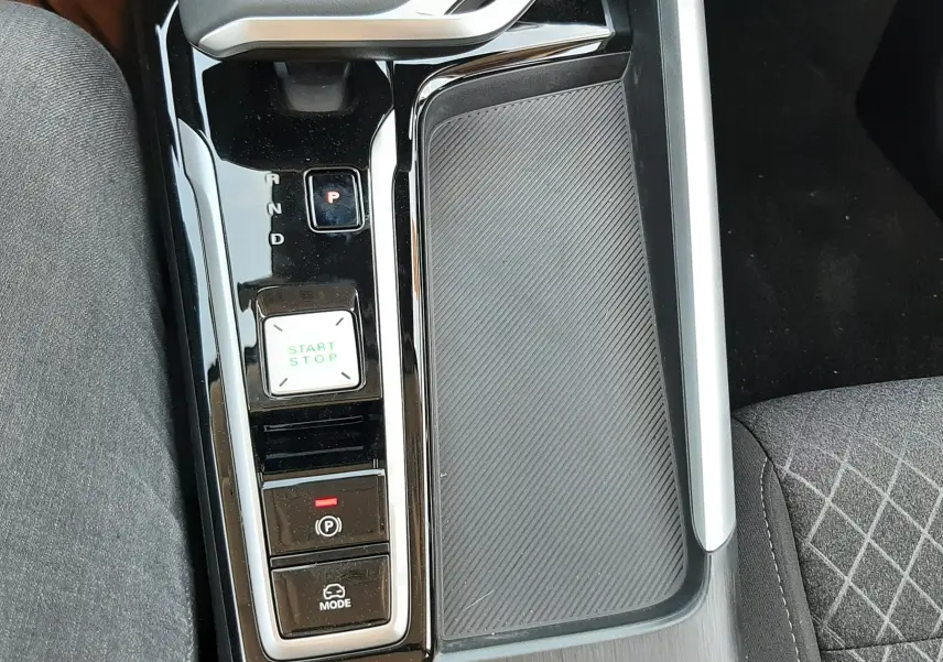 Vue rapprochée de la console centrale noire brillante du MG ZS 1.5L Hybrid+ avec bouton start/stop et levier de vitesses automatique.