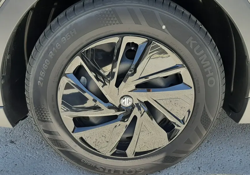 Gros plan sur la roue avant gauche noire brillante du MG MOTOR ZS 1.5L HYBRID+ 197CH avec jante au design moderne.