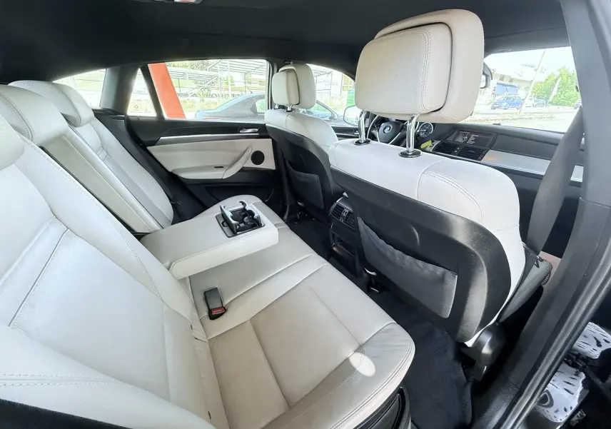 Vue intérieure arrière droite du BMW X6 2011 avec sièges en cuir beige et accoudoir central déployé.