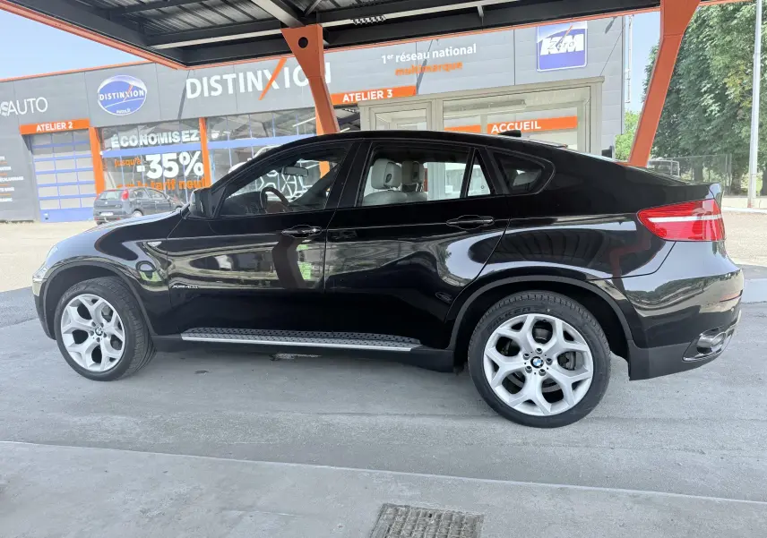 BMW X6 noire vue de profil côté gauche, soulignant ses jantes argentées et sa silhouette coupé SUV.