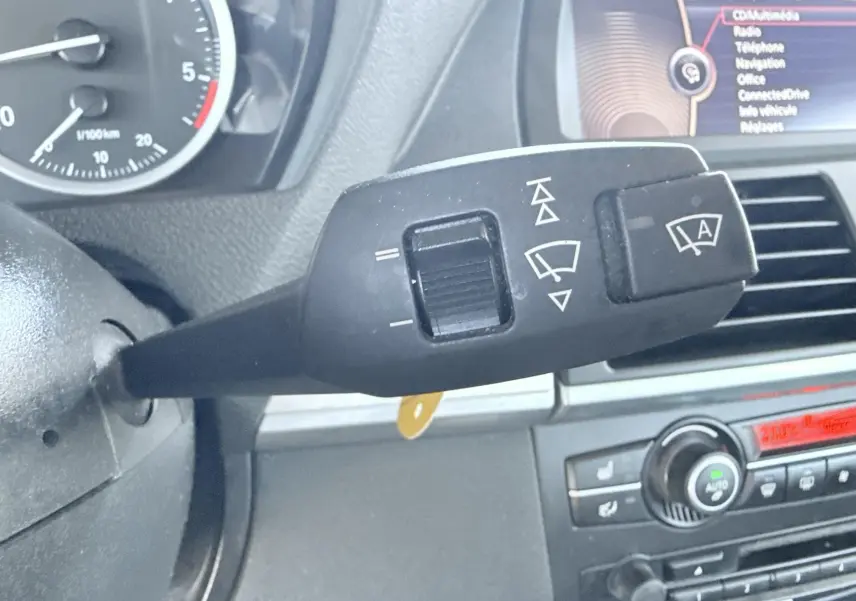 Gros plan sur la commande d’essuie-glace à gauche du volant dans l’habitacle noir d’une BMW X6 noire de 2011.