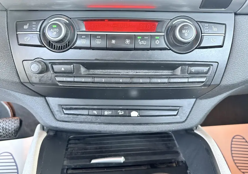 Vue rapprochée du tableau de bord noir de la BMW X6 2011, montrant les commandes de climatisation et audio.
