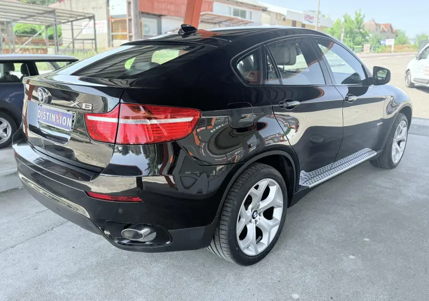 BMW X6 noire vue 3/4 arrière droit, avec jantes argentées et marchepieds métalliques sous les portières.