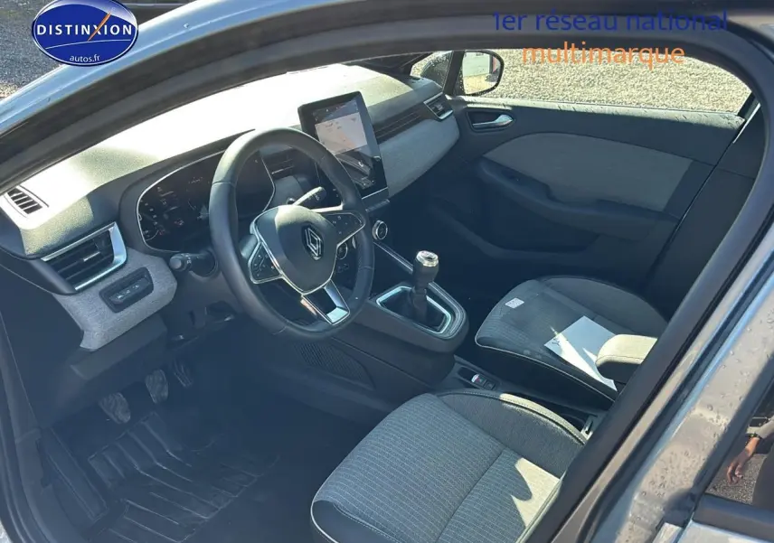 Intérieur de la Renault Clio V gris pizarra vu côté conducteur, volant textile et levier de vitesses manuel visibles.