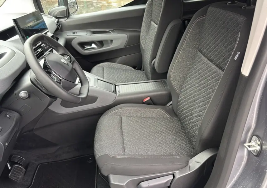 Intérieur avant du Peugeot Rifter gris artense, vue côté conducteur montrant sièges tissu et tableau de bord moderne.