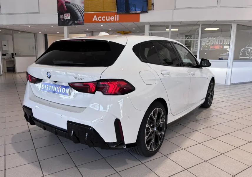 Vue 3/4 arrière droite d'une BMW Série 1 120d M Sport blanche, avec jantes sport et diffuseur noir, en showroom.