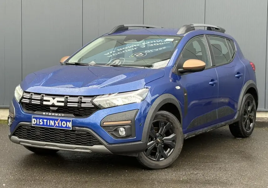 Vue 3/4 avant droite d'une Dacia Sandero Stepway Bleu Iron avec jantes noires et coques de rétroviseurs cuivrées.