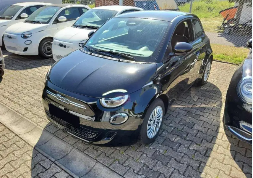 Fiat 500 électrique noire vue 3/4 avant droit, avec phares ronds et calandre chromée distinctive.