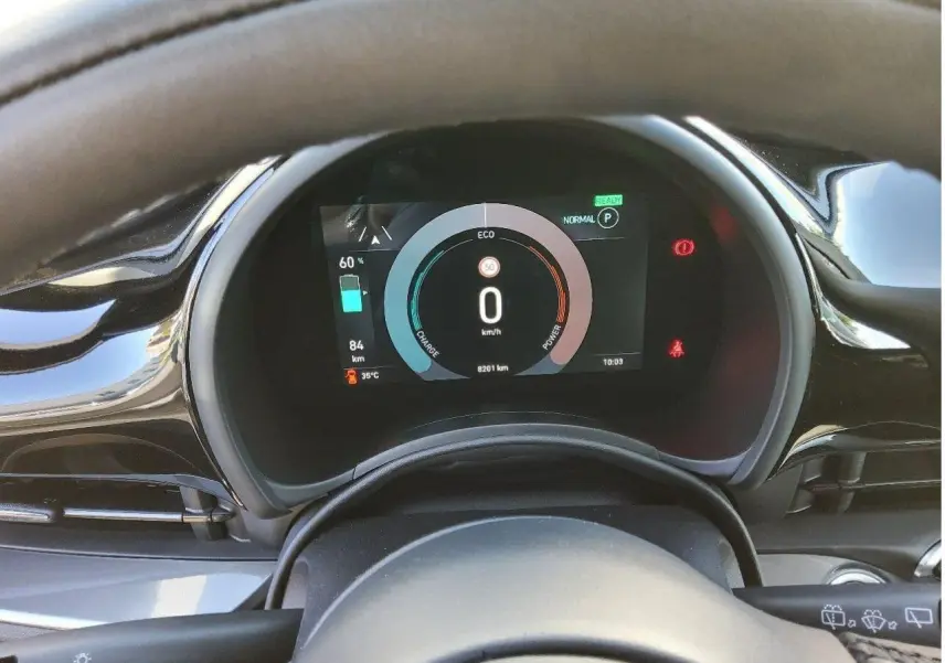 Vue rapprochée du tableau de bord numérique de la Fiat 500 électrique 2024, affichant l'autonomie et la vitesse à 0 km/h.