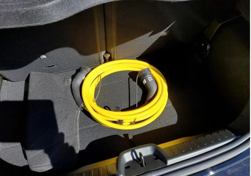 Coffre ouvert d'une FIAT 500 électrique noire avec câble de recharge jaune enroulé visible au centre.