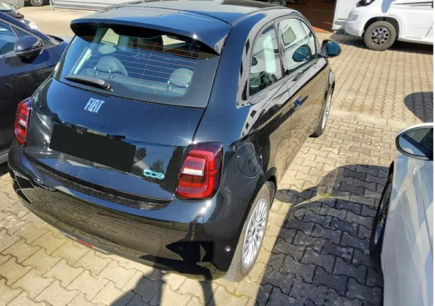 Vue 3/4 arrière droite d'une Fiat 500 électrique noire 2024 avec logo 500 bleu et feux arrière LED.