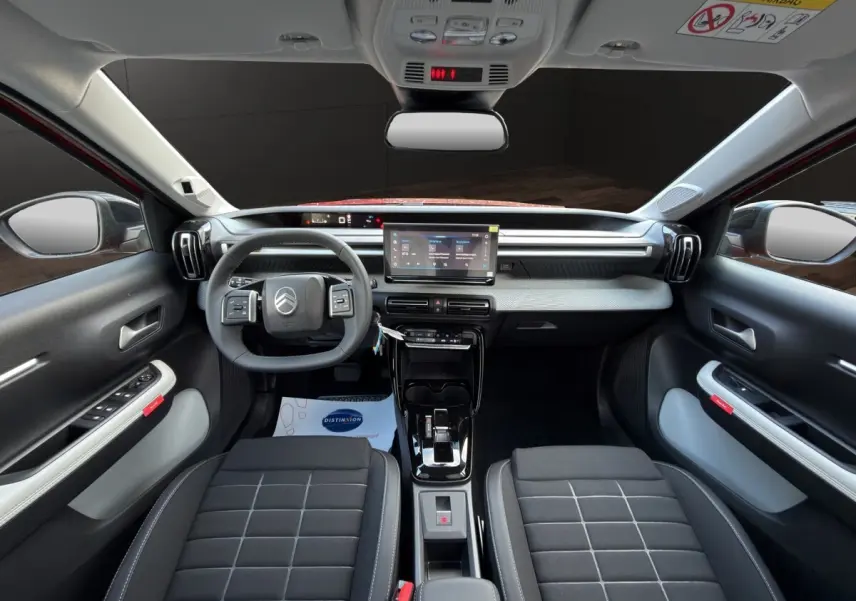 Vue intérieure avant de la Citroën C3 rouge 2026, tableau de bord moderne avec écran tactile et volant cuir multifonctions.
