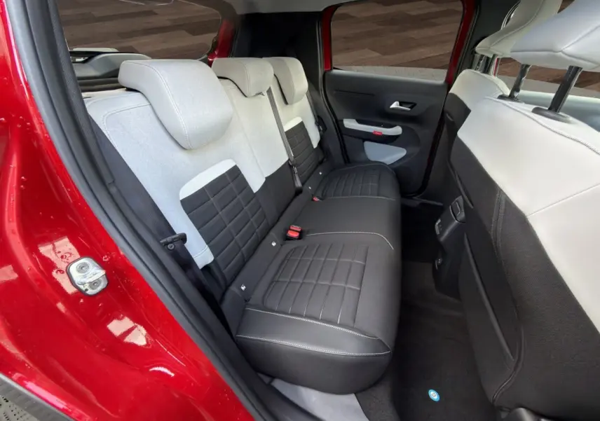 Vue intérieure arrière côté gauche de la Citroën C3 rouge 2026, banquette bicolore noire et grise avec appuie-têtes.
