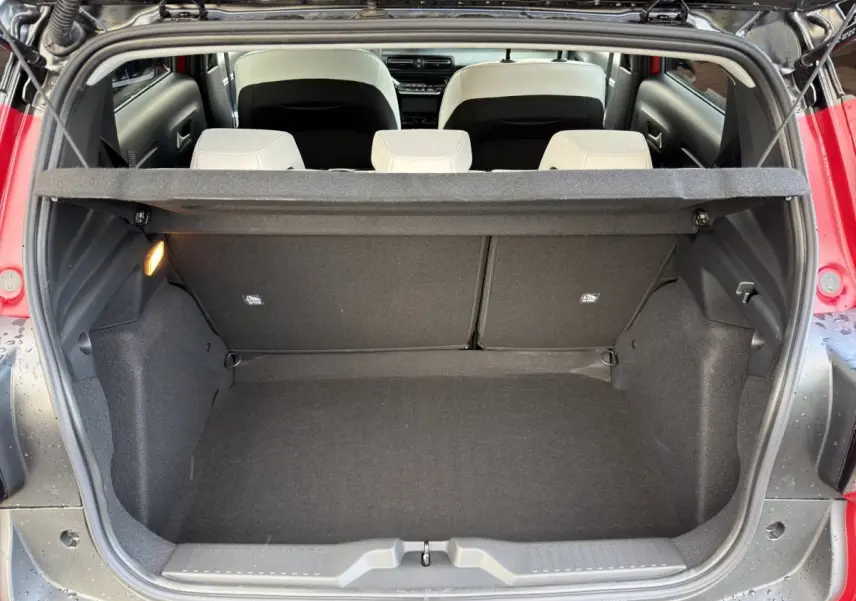 Vue arrière du coffre ouvert d'une Citroën C3 rouge hybride 2026, avec banquette arrière beige et tablette de coffre.