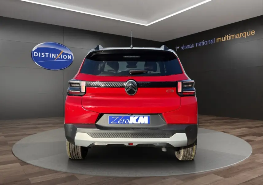 Vue arrière d'une Citroën C3 rouge 2026 avec logo noir et bande noire distinctive sous la lunette arrière.