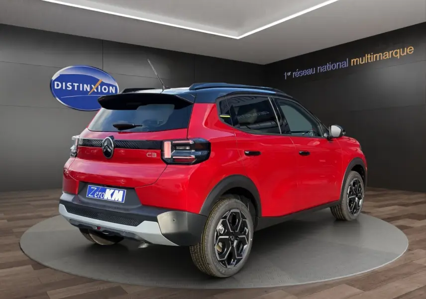 Vue 3/4 arrière droite d'une Citroën C3 hybride rouge avec toit noir et jantes noires distinctives.