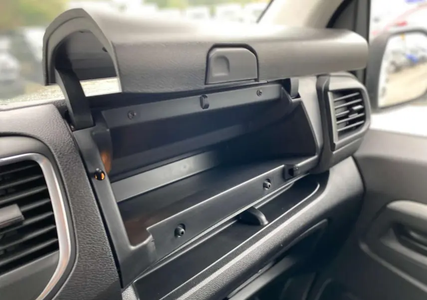 Intérieur du Peugeot Expert Fourgon blanc 2023, vue rapprochée du rangement ouvert côté passager avec tableau de bord noir.