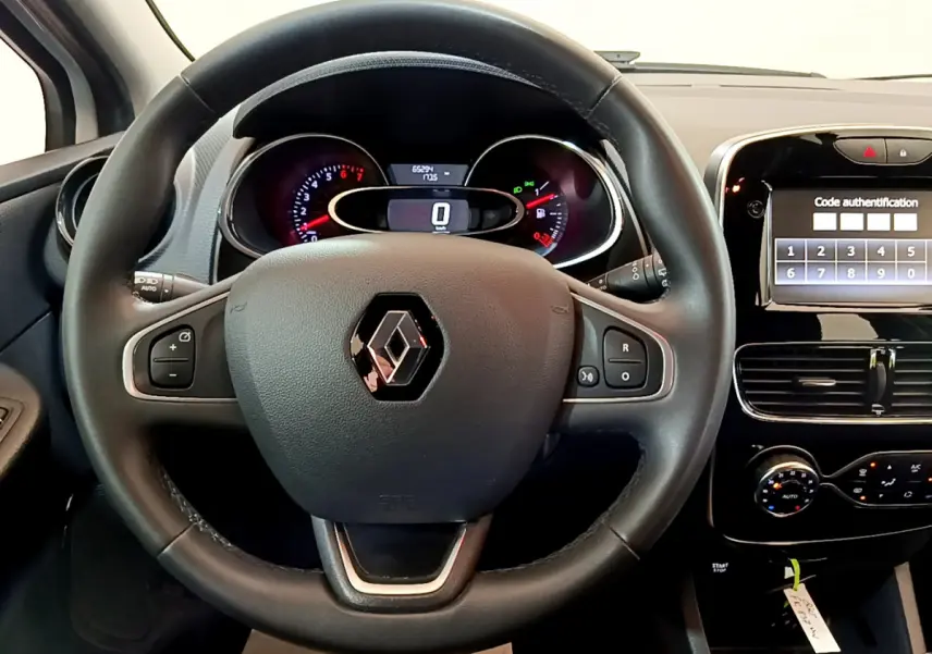 Vue intérieure centrée sur le volant cuir noir de la Renault Clio Business avec tableau de bord et écran tactile allumé.