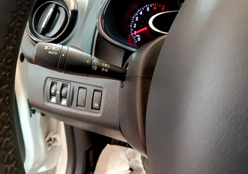 Gros plan sur le volant et la commande des feux de la Renault Clio Business TCe 90 blanche de 2019, intérieur noir.