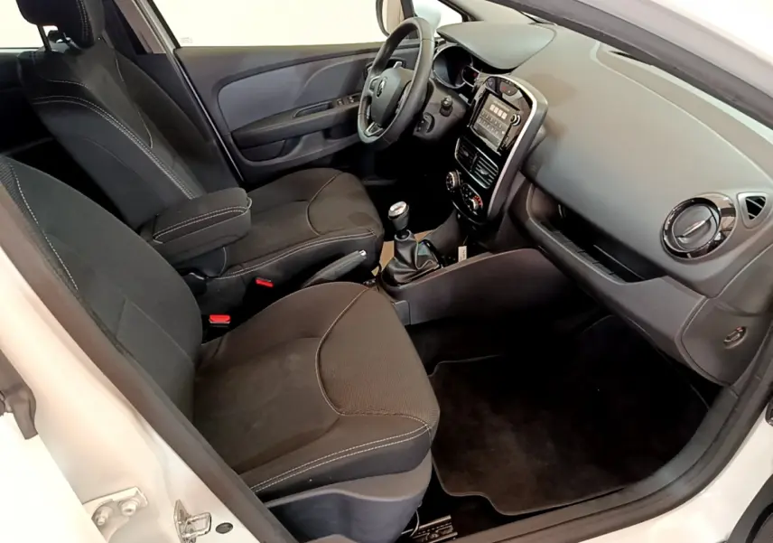 Intérieur de la Renault Clio Business TCe 90 blanc, vue côté conducteur montrant sièges noirs et tableau de bord tactile.