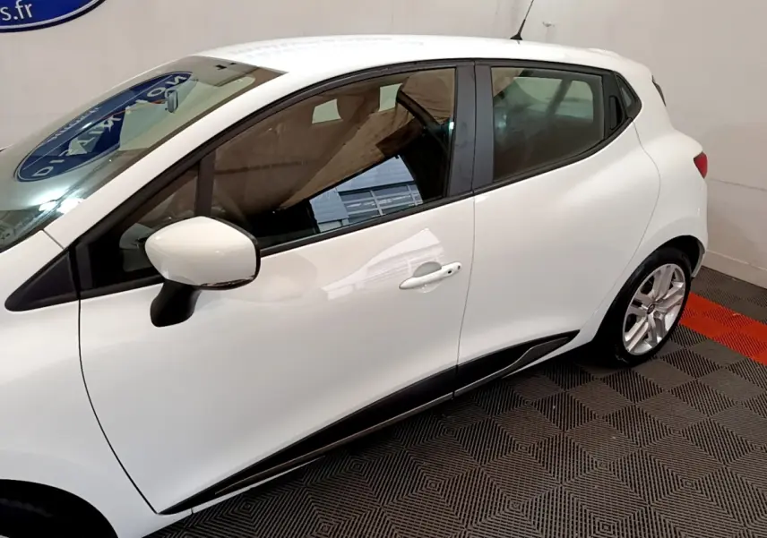 Profil côté gauche d'une Renault Clio Business TCe 90 blanche, avec rétroviseur et jante alliage visibles.