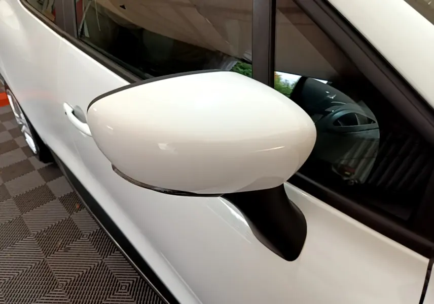 Gros plan sur le rétroviseur côté gauche blanc d'une Renault Clio Business TCe 90 blanche, avec porte et vitre visibles.