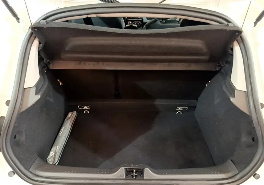Coffre ouvert de la Renault Clio Business TCe 90 blanche, vue arrière montrant l'espace de rangement noir et la tablette de coffre.