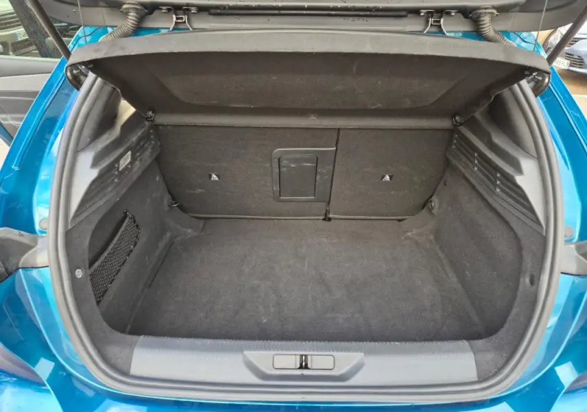 Coffre ouvert vu de l'arrière d'une Peugeot 308 bleu 2024, montrant un espace de chargement propre et spacieux.