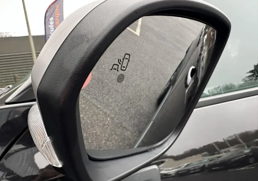 Rétroviseur extérieur côté gauche du Dacia Duster noir 2025 avec indicateur d'angle mort intégré.