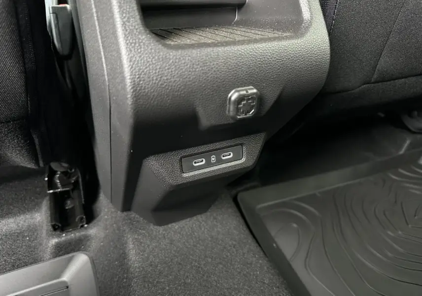 Prise USB type C arrière sur console centrale noire du Dacia Duster 2025, vue rapprochée côté droit arrière.