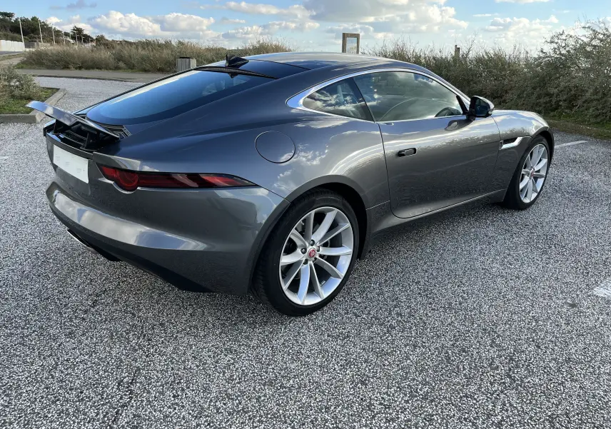Jaguar F-TYPE II Coupé gris Corris vue 3/4 arrière droit avec aileron arrière relevé et jantes 19 pouces.