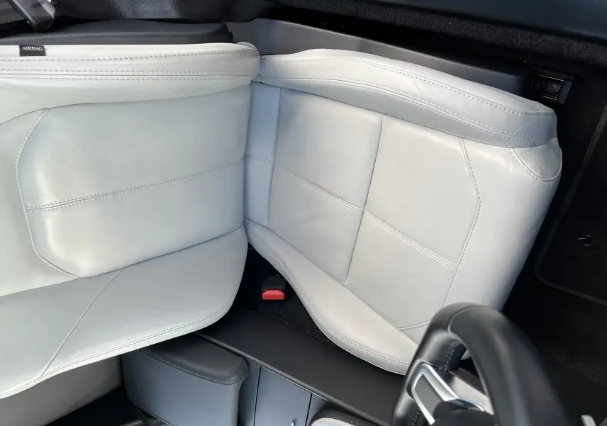 Gros plan sur le siège avant gauche en cuir clair de la Jaguar F-TYPE II Coupé, avec partie du volant noir visible.