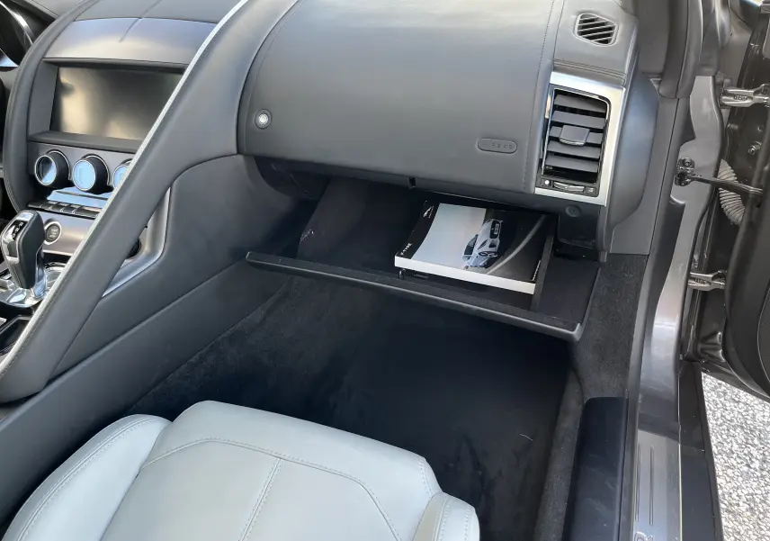 Vue intérieure côté passager de la Jaguar F-TYPE II Coupe 2.0T 2018 gris Corris, boîte ouverte avec manuel visible.